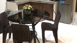 A compact kitchen with a dining table and chairs, a refrigerator, and various kitchen appliances. - Cranberry's Place (Iloilo)