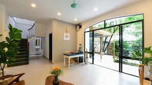 Una habitación amplia con escaleras, un comedor y grandes ventanales que ofrecen vistas al exterior.