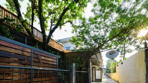 Un estrecho callejón con una cerca de madera a un lado y un muro de concreto al otro, que conduce a la entrada de un edificio.