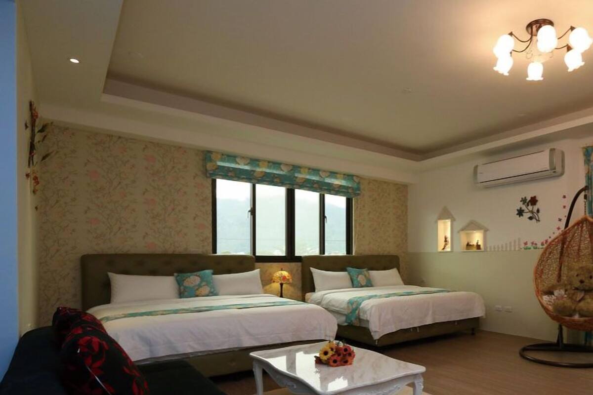Een hotelkamer met twee bedden, een bank, een kleine tafel en een hangstoel.
