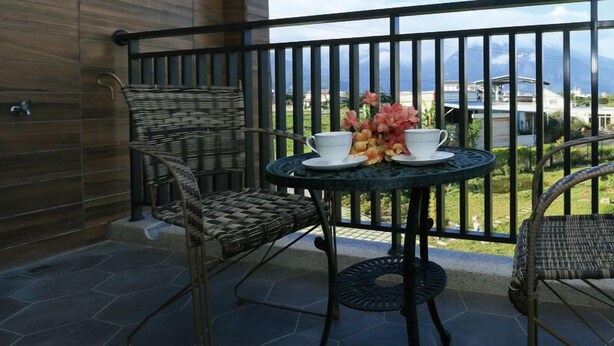 A balcony with wicker chairs, a small round table, and a vase of flowers. - Jifun Flower Meanings (Ji'an)