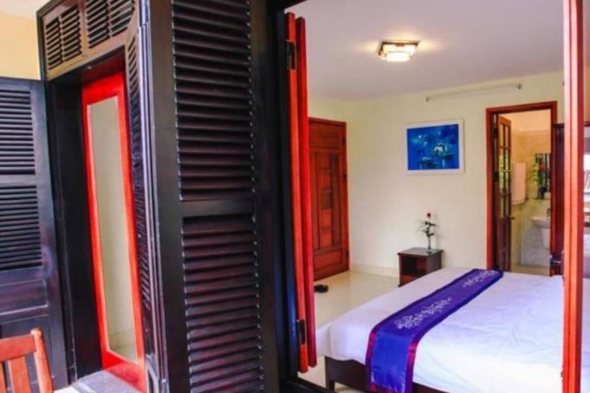 A room with a bed, a nightstand, and a window with blinds.