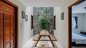 A hallway with a stone wall, wooden door, and a bed in the adjacent room. - Harmony Homestay (Da Nang)