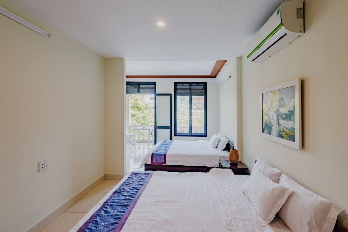 A hotel room with two beds, a balcony, and an air conditioning unit.