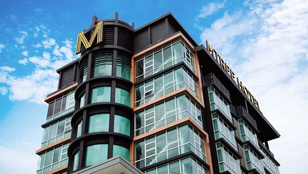 Un moderno edificio de hotel con un llamativo logo 'M' y la señalización 'MINTREX HOTEL'.