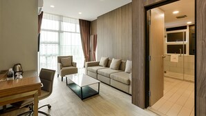 Habitación de hotel moderna con sofá, una mesita de café, un escritorio con hervidor y vistas al baño.