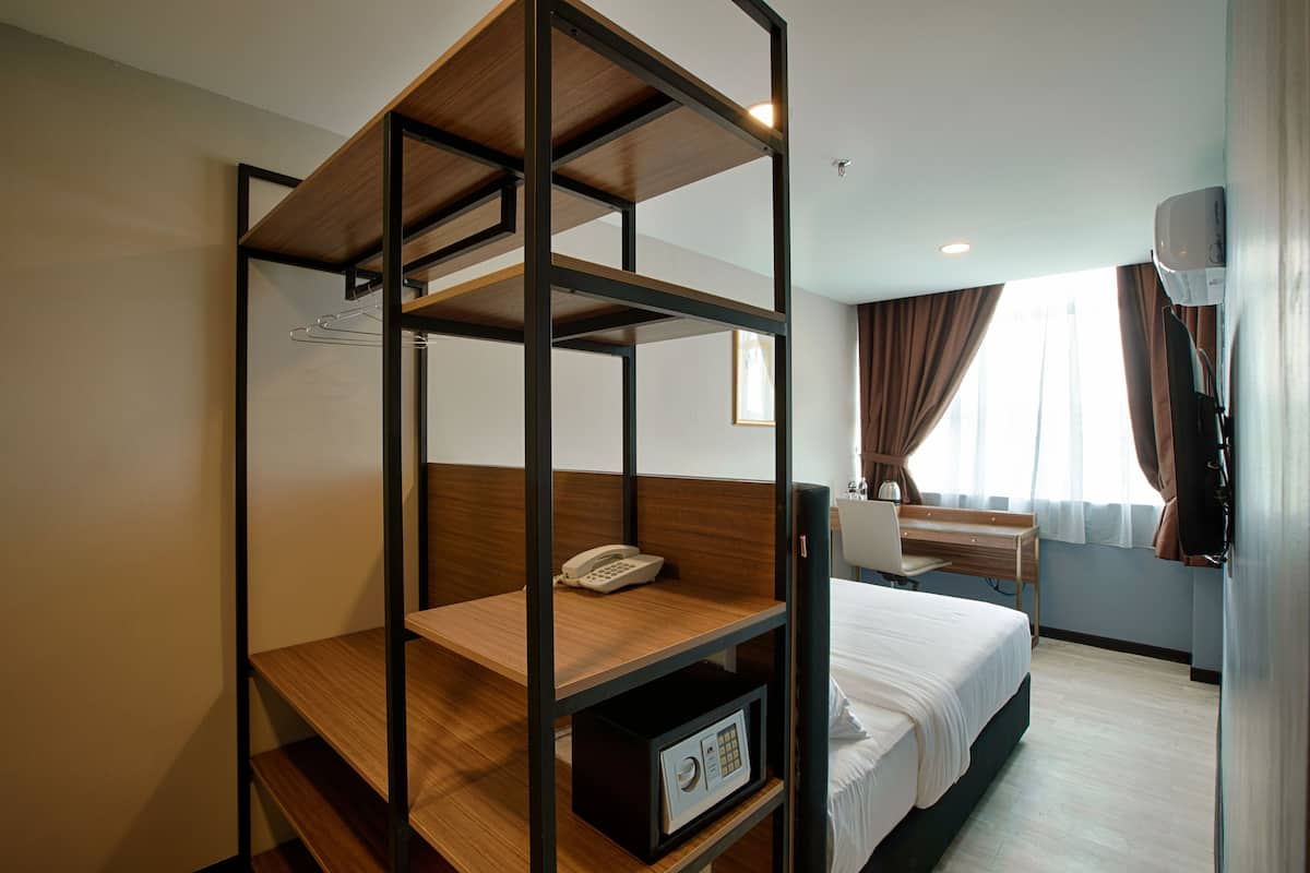 Une chambre d’hôtel avec un lit superposé, un bureau avec une chaise, une table de chevet et une armoire.