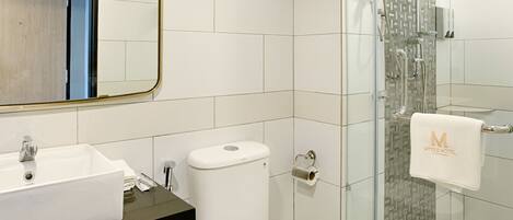 Un baño moderno con lavamanos, inodoro y ducha con cerramiento de vidrio.