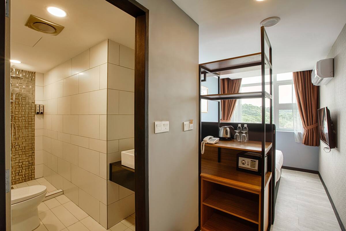 Une salle de bain moderne équipée d’une douche, de toilettes et d’un petit coin salon avec un téléphone et des bouteilles.