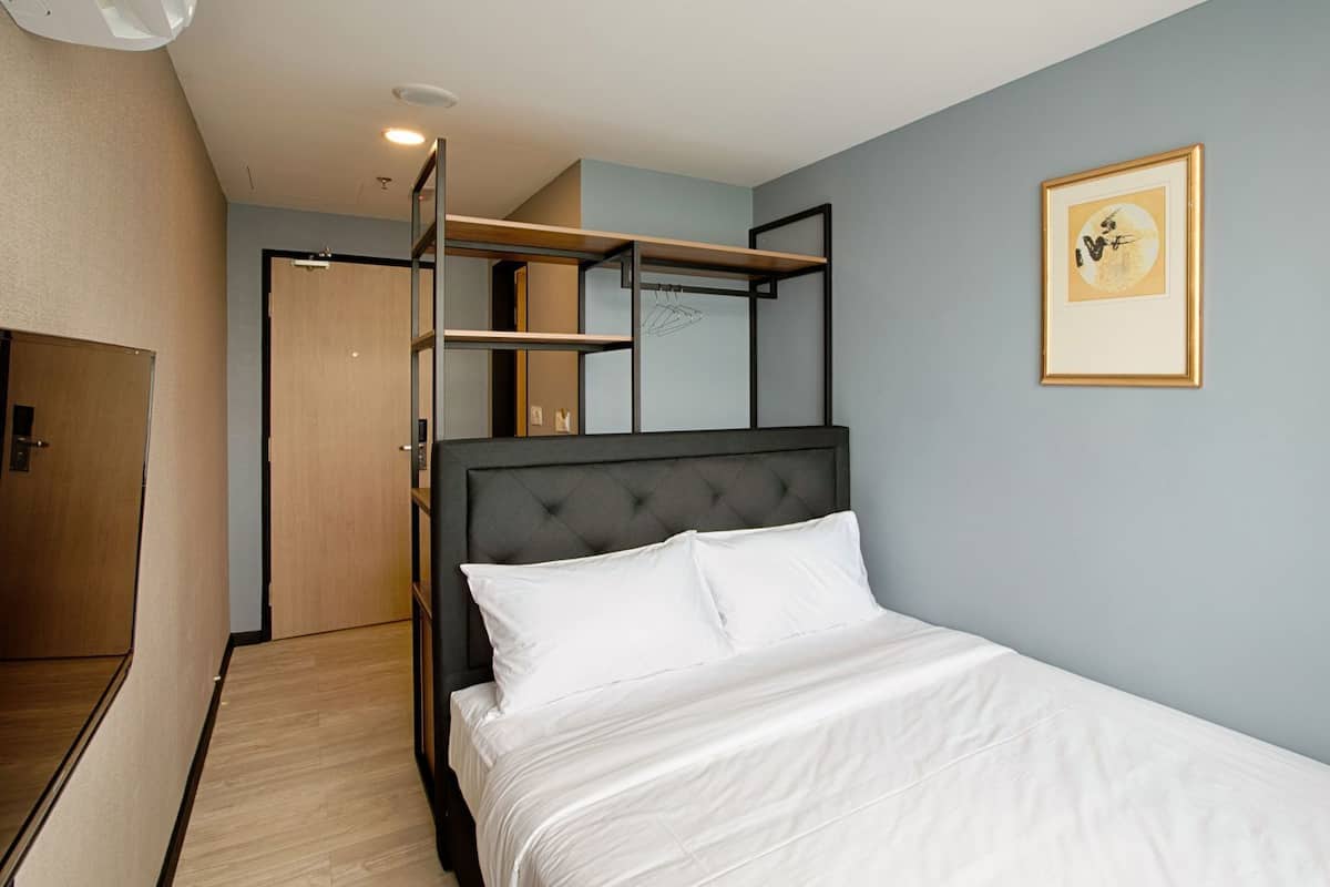 Une chambre à coucher avec un lit, une armoire, une porte et un tableau encadré au mur.