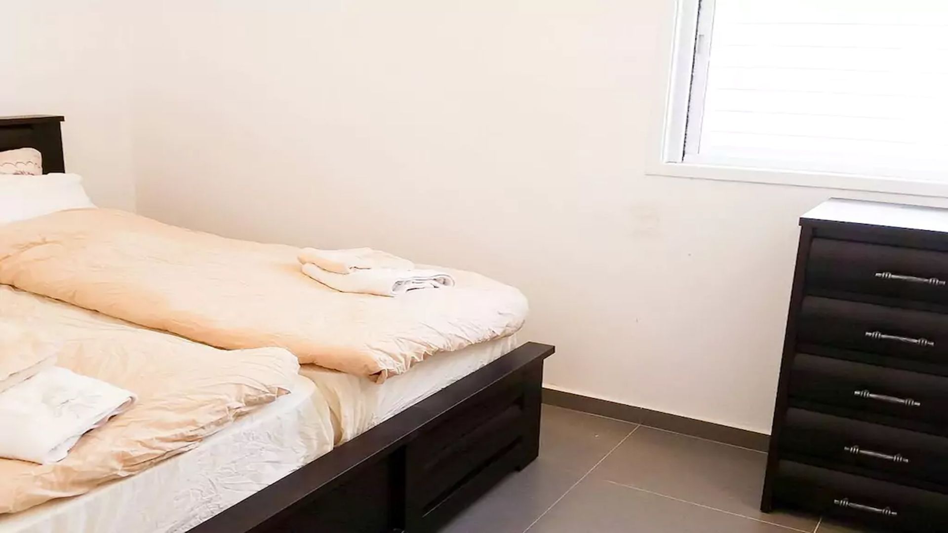A bedroom with a bed, a dresser, and a window.