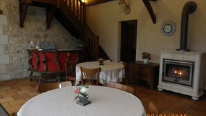 A cozy room with a fireplace, wooden staircase, and a dining area with a table and chairs.