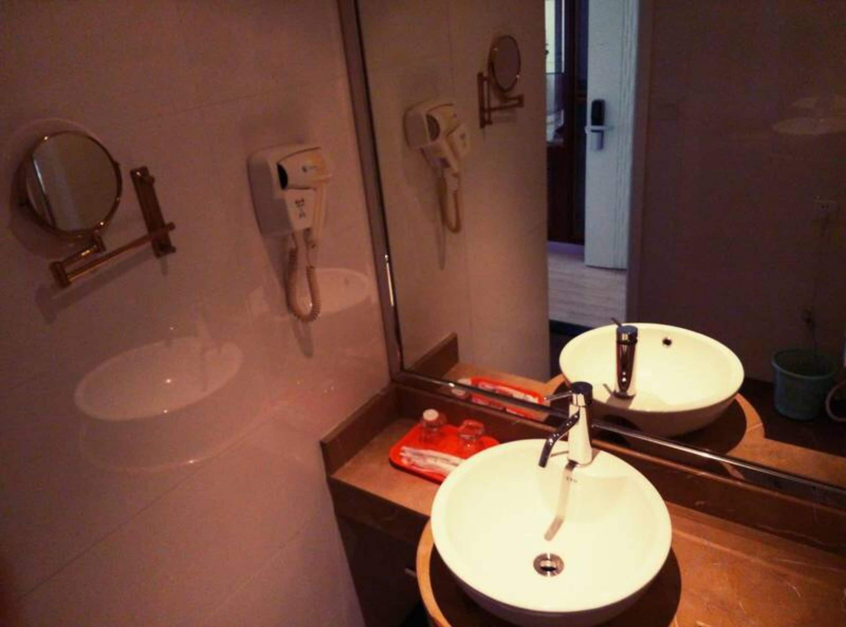 Ein Badezimmer mit zwei Waschbecken, einem Spiegel, einem Händetrockner und einer Seifenspender.