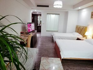 Habitación de hotel con dos camas, un escritorio con televisor, una planta en maceta y una ventana con cortinas.