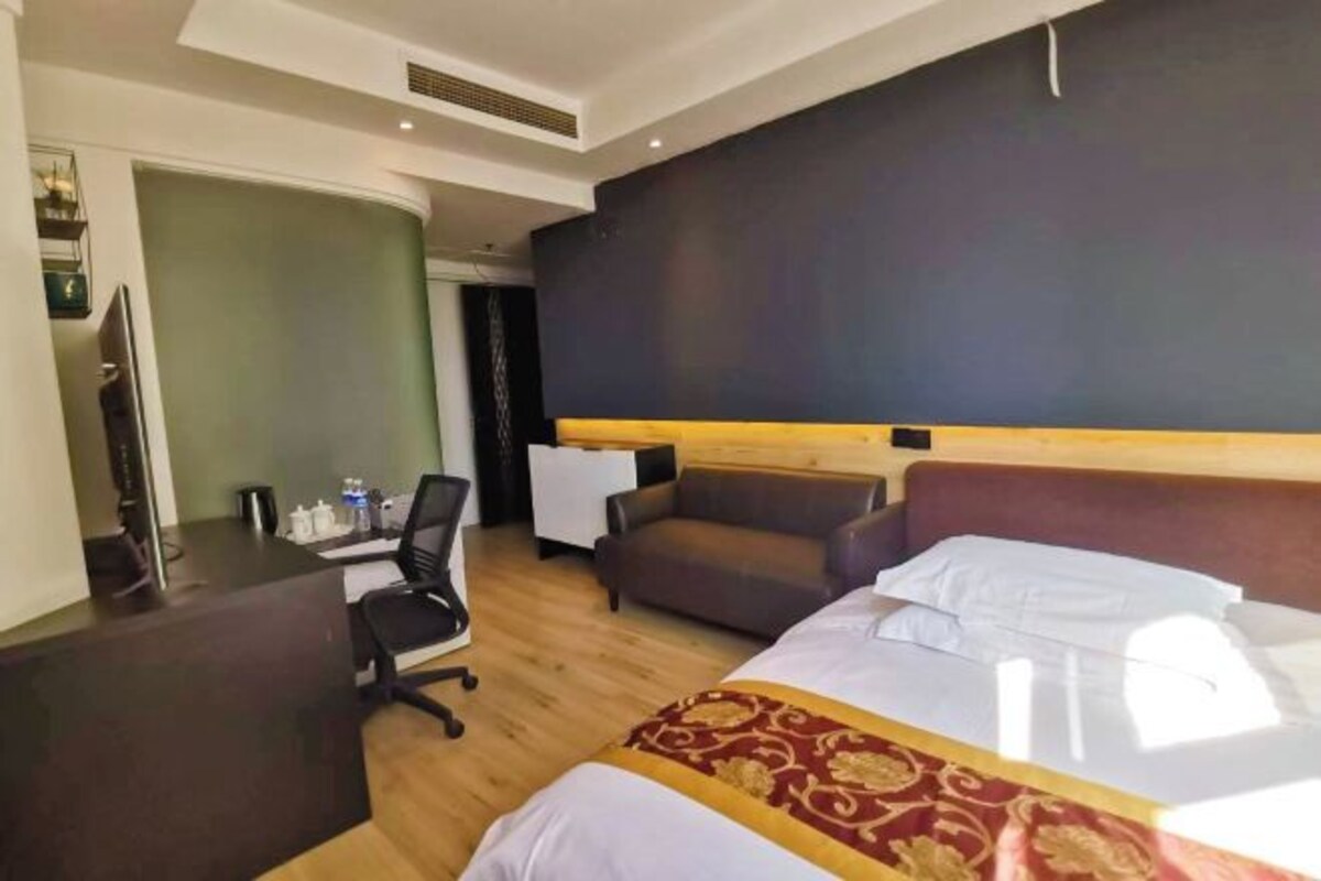 A hotel room with a bed, a desk, a chair, and a sofa.