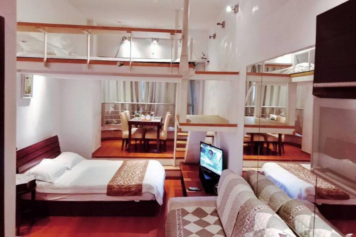A modern hotel room with a loft bed, a dining area, and a TV.