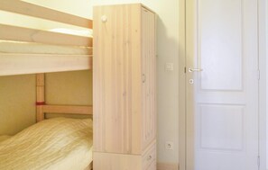 A bunk bed with a wooden wardrobe next to a white door.