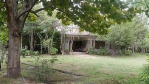 A rustic house with a stone exterior, surrounded by lush greenery and trees.