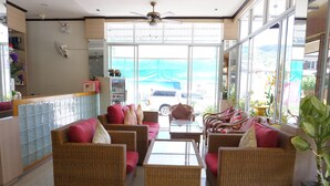 Amplia sala de estar con muebles de mimbre, una mesa de centro de vidrio y vistas al exterior.