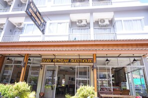 Una casa de huéspedes con letrero, ventanas amplias y un balcón.