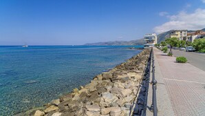 A coastal road with a stone seawall, clear blue sea, and buildings along the side. - Nice apartment in Acciaroli with house sea view (Acciaroli)