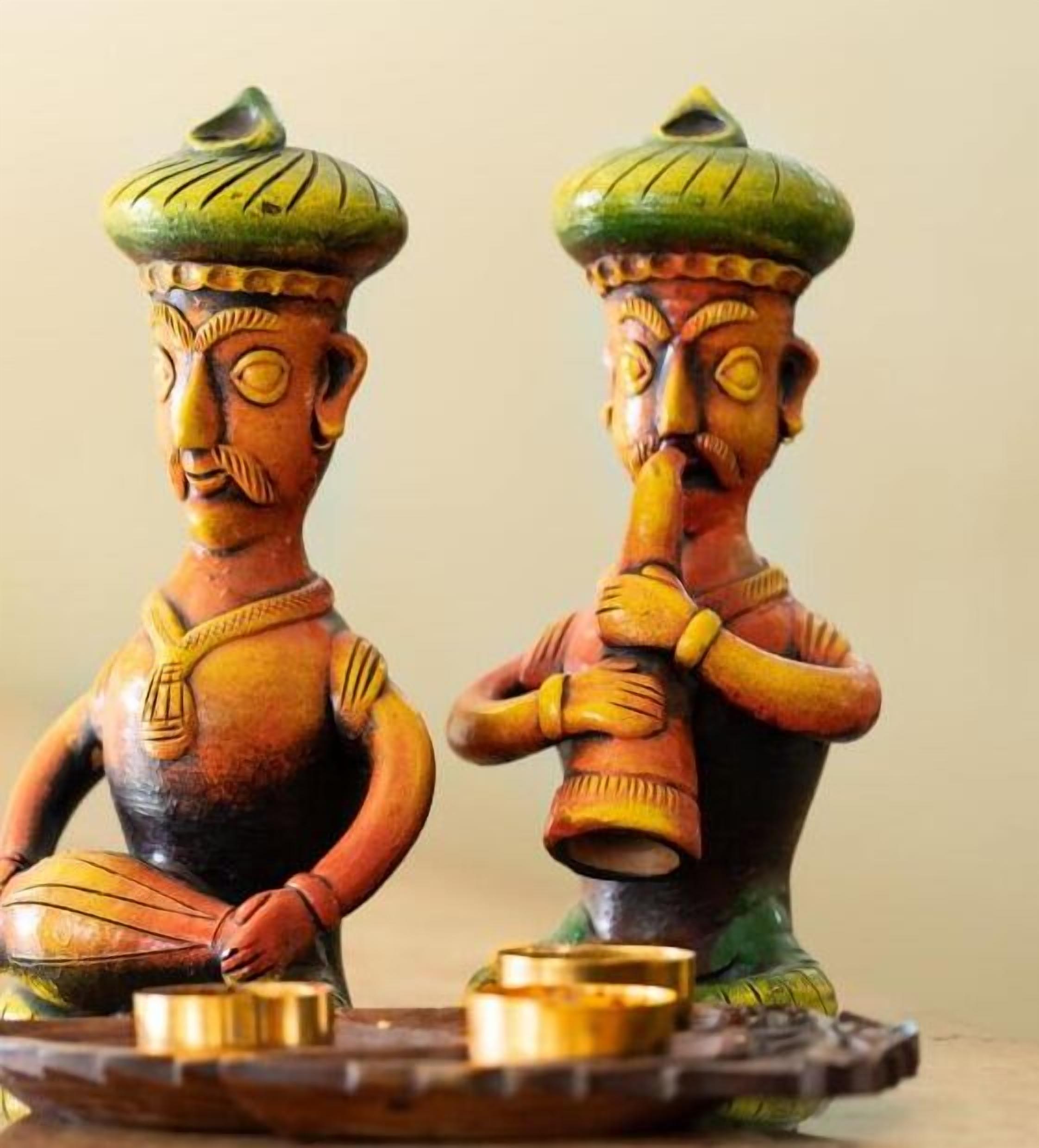 Dos figuritas de madera con atuendo tradicional y una bandeja con pequeños recipientes.