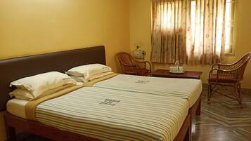 Una habitación de hotel con una cama, dos sillas, una mesa y un ventanal con cortinas.
