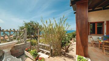 Patio con vista sul mare, un tavolo in legno e piante in vaso.