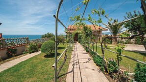 A garden pathway leading to a house with a view of the sea. - Beach front apartment in Porto Alabe (Porto Alabe)