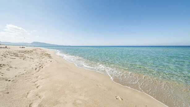 A beach with clear water, a sandy shore, and distant mountains. - Beach front apartment in Porto Alabe (Porto Alabe)