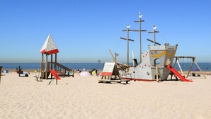 A beach with a lifeguard tower and a wooden play structure. - Residentie De Kateie ref 15 (Ooostende)