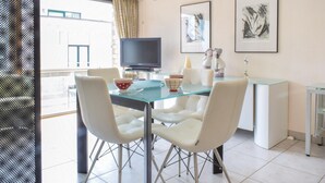 A modern dining area with a glass table, white chairs, a television, and artwork on the walls. - Residentie De Kateie ref 15 (Ooostende)