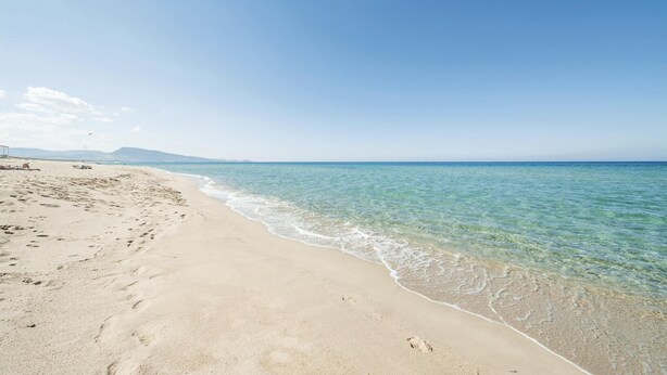 Ein Strand mit klarem Wasser und einem Sandufer.