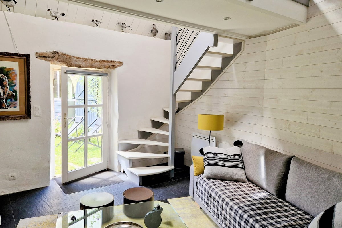 A spacious living area with a staircase, a sofa, a coffee table, and a painting on the wall.