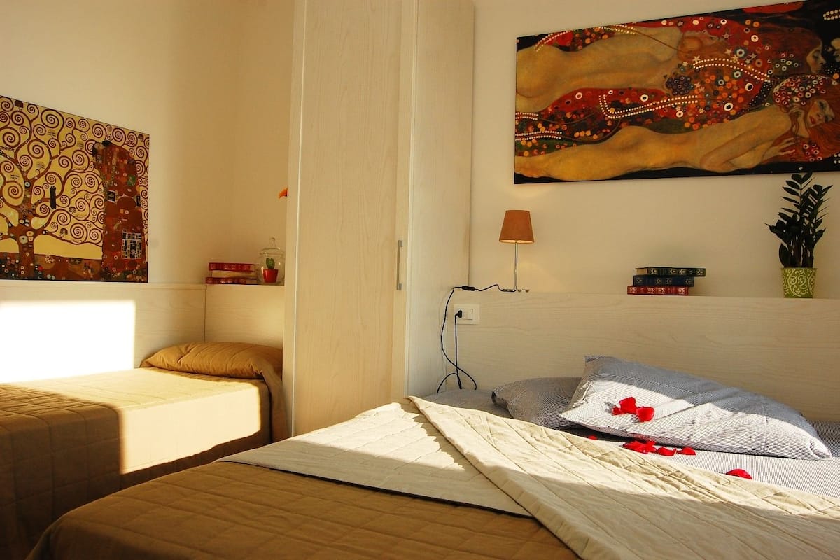 Ein Schlafzimmer mit zwei Betten, einem Bild, einer Lampe und einer kleinen Pflanze.