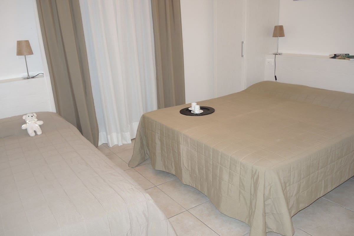 Ein Hotelzimmer mit zwei Betten, einem kleinen Tisch und einem Teddybären auf einem Bett.