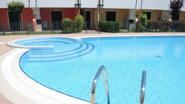En pool med en böjd kant och en kakelbeklädd poolkant.