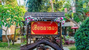 A wooden structure with a red sign in a garden setting. - Huandalha Resort Lumphun (Lamphun)