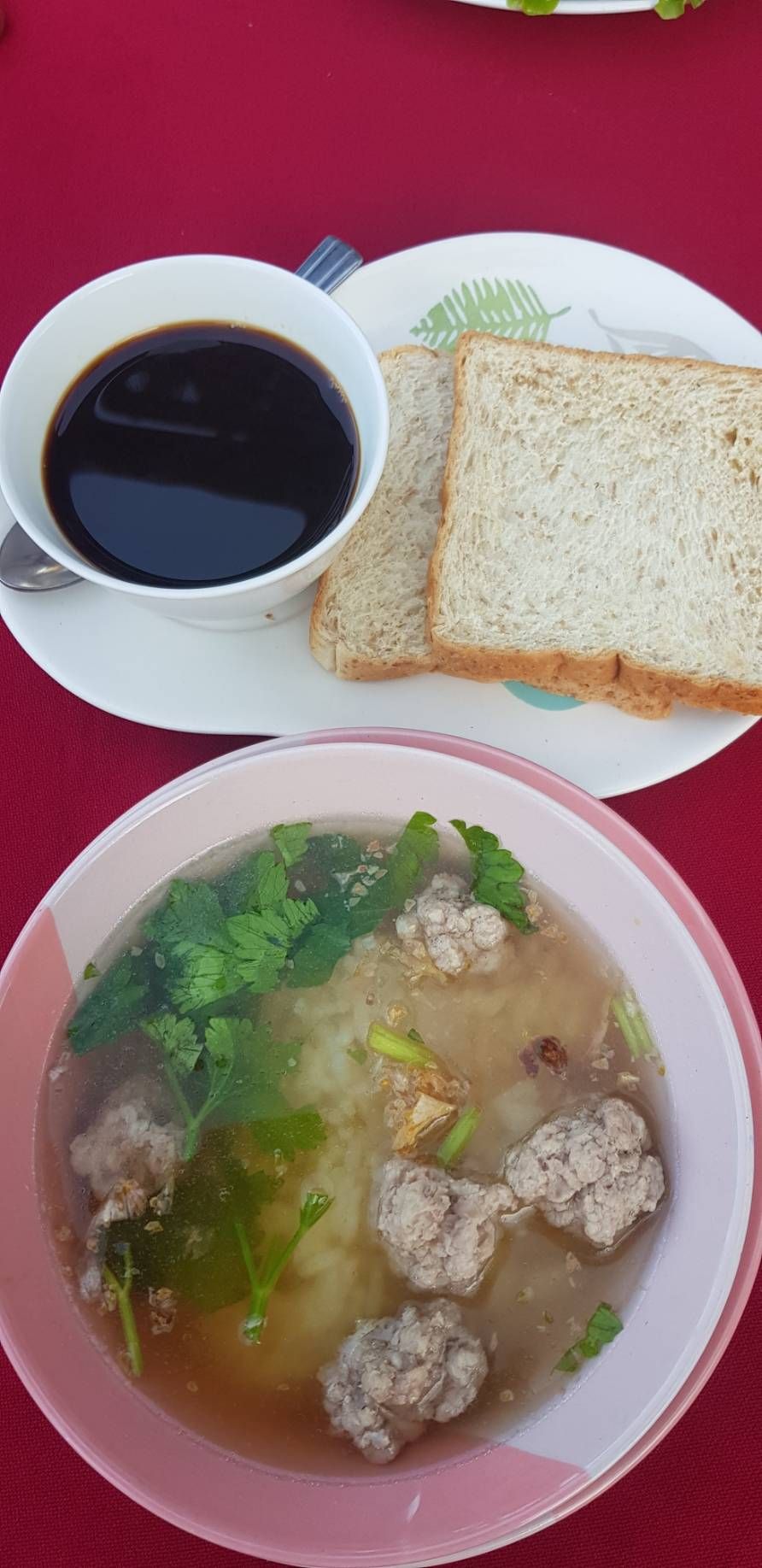 Comida que incluye sopa con albóndigas, pan y una taza de café.