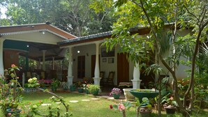 A covered outdoor area with potted plants and a building with columns. - Sigiri Lodge (Sigiriya)