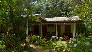 A traditional building with a tiled roof, surrounded by lush greenery and potted plants. - Sigiri Lodge (Sigiriya)