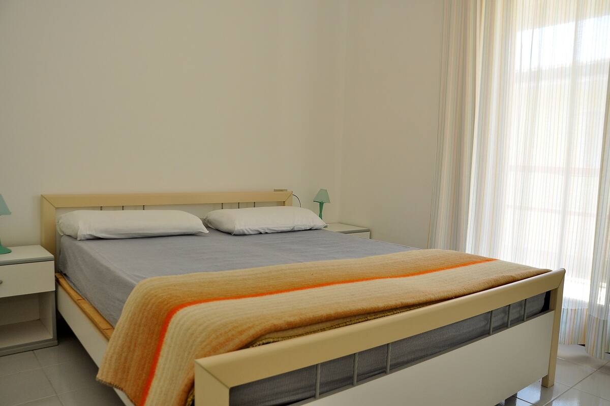 A bedroom with a bed, nightstands, and a lamp.