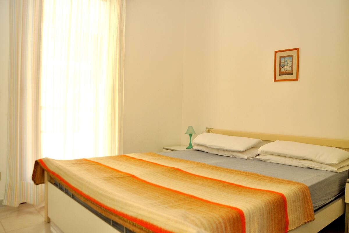 A bedroom with a bed, a nightstand, a lamp, and a framed picture on the wall.