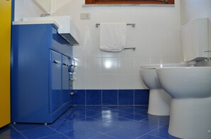 A bathroom with a blue cabinet, a white toilet, and a white towel hanging on a rack.
