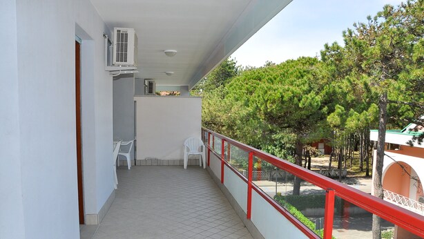 A balcony with a tiled floor, white chairs, and a red railing. - Condominio Tucano (San Michele al Tagliamento)