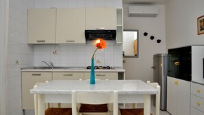 A modern kitchen with white cabinets, a marble countertop, and a gas stove. - Condominio Tucano (San Michele al Tagliamento)