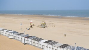 A beach with a lifeguard tower, a row of beach huts, and a clear view of the ocean. - Costa Brava 3e Ref. Nr 202 (Oostende)