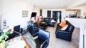A modern living room with a sofa, chairs, a dining table, and a kitchen area. - Costa Brava 3e Ref. Nr 202 (Oostende)