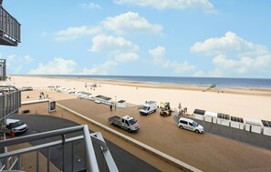 Uitzicht op een strand vanaf een verhoging, met een verharde looppad, strandparasols en mensen op het strand.