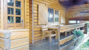 Une cabane en bois avec une véranda, un banc et une table.
